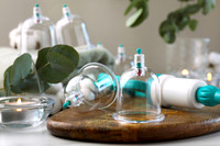 Plastic cups and hand pump on white table. Cupping therapy